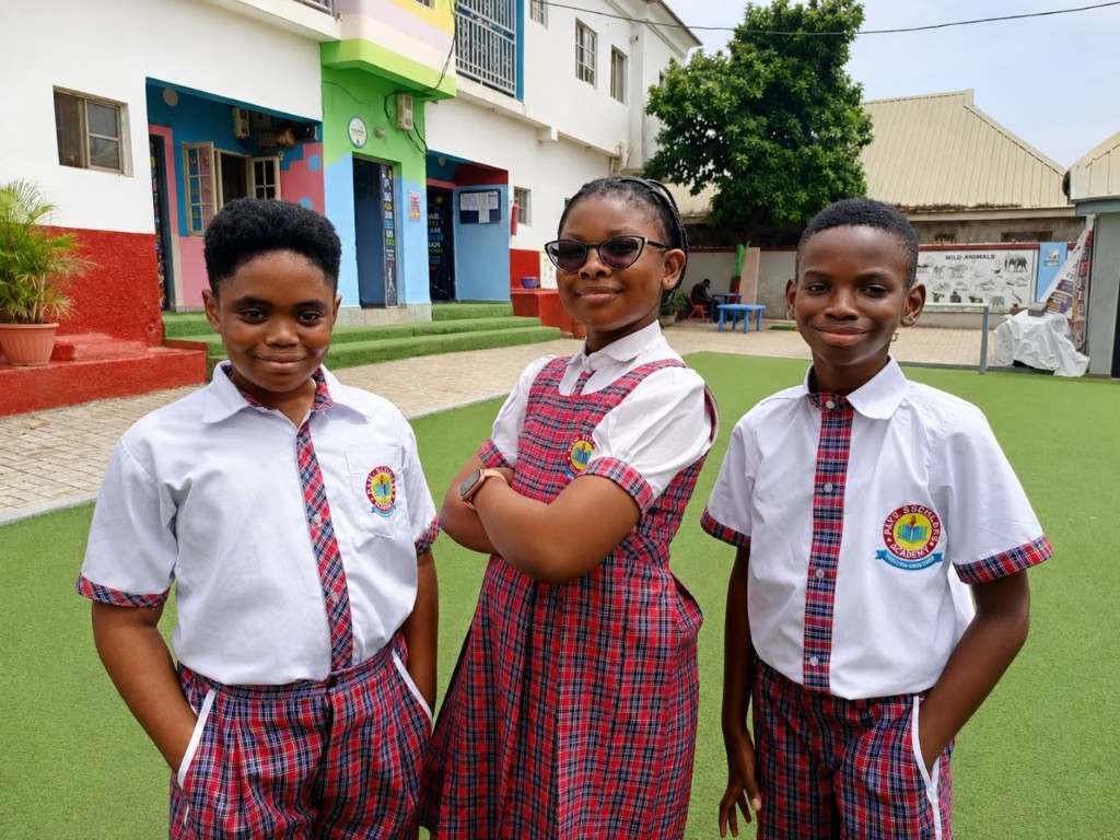 Three Pave Scholars pupils in check uniform on the front field