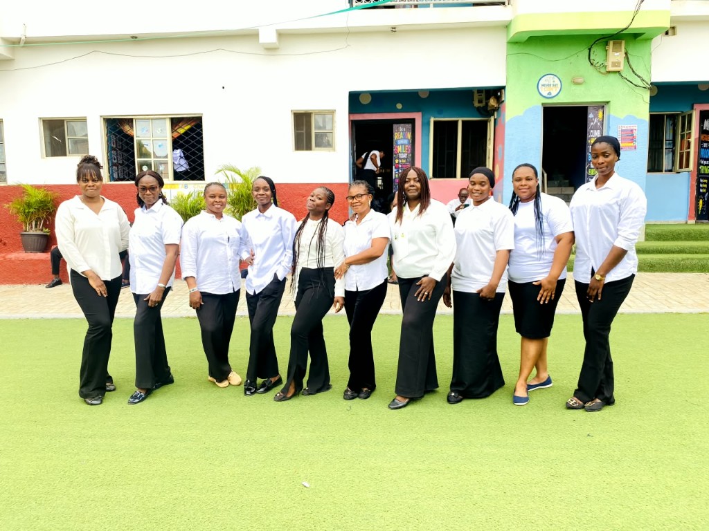 Teachers in white shirts standing together on the front field